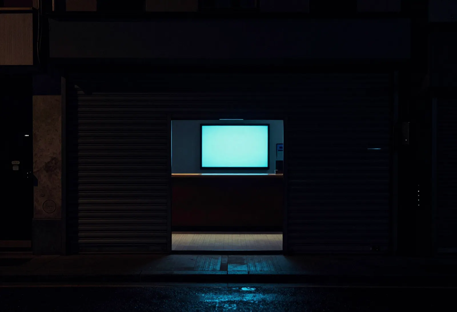 A closed shop at night, a single screen glowing.
